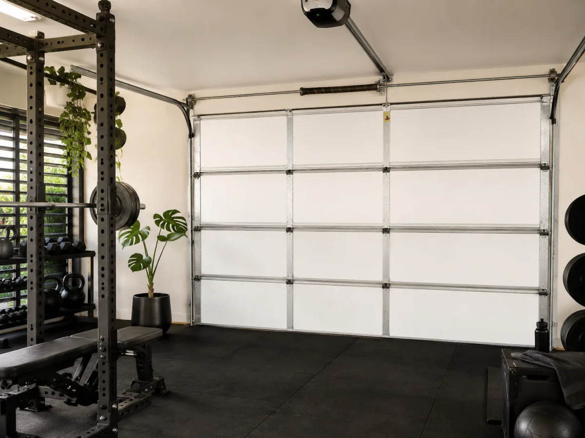 Insulated garage converted into a modern home gym, closed matte white KoolDoor panel door visible