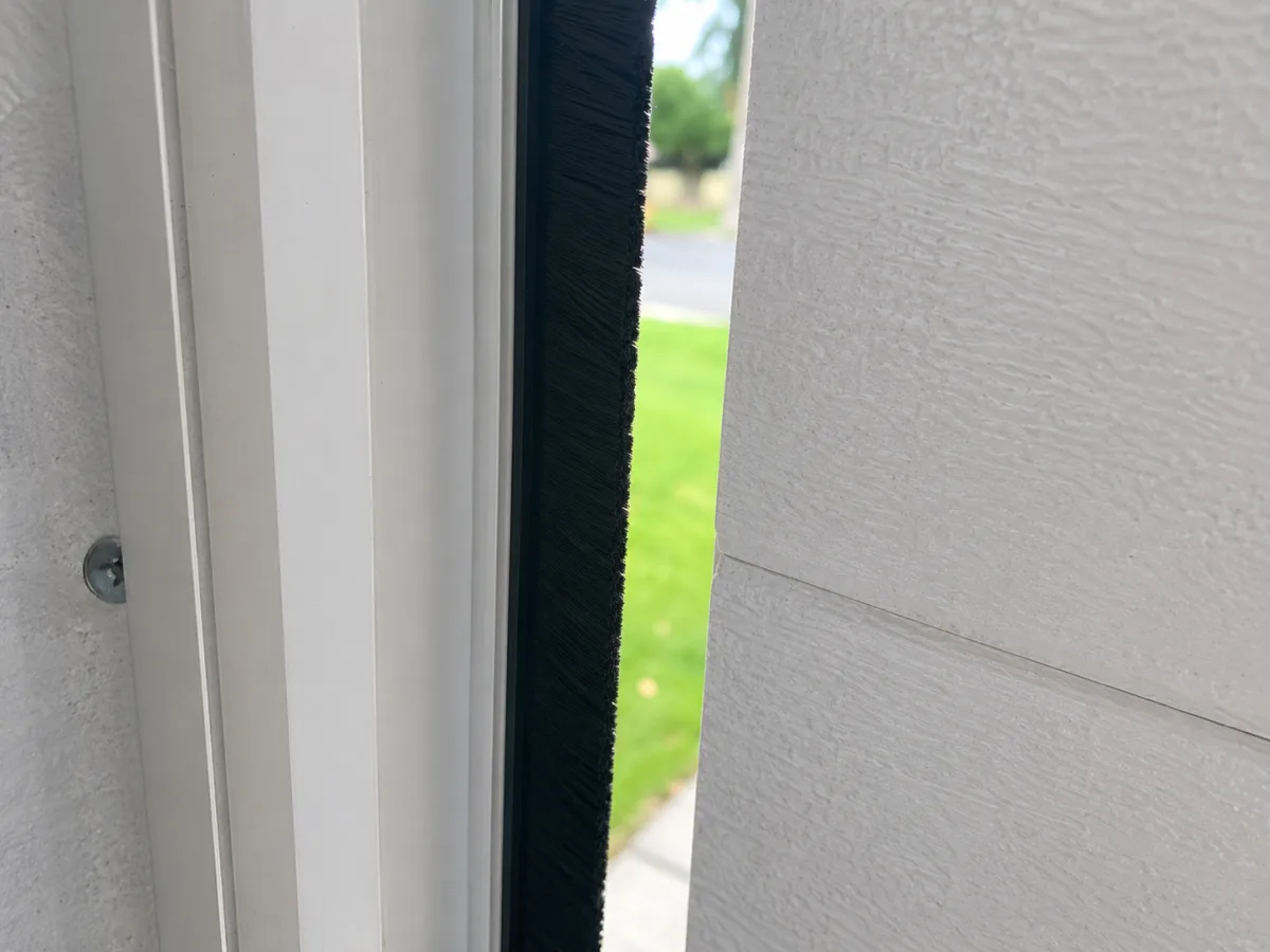 Black brush side seal fitted vertically along a garage door jamb, closing a small side gap